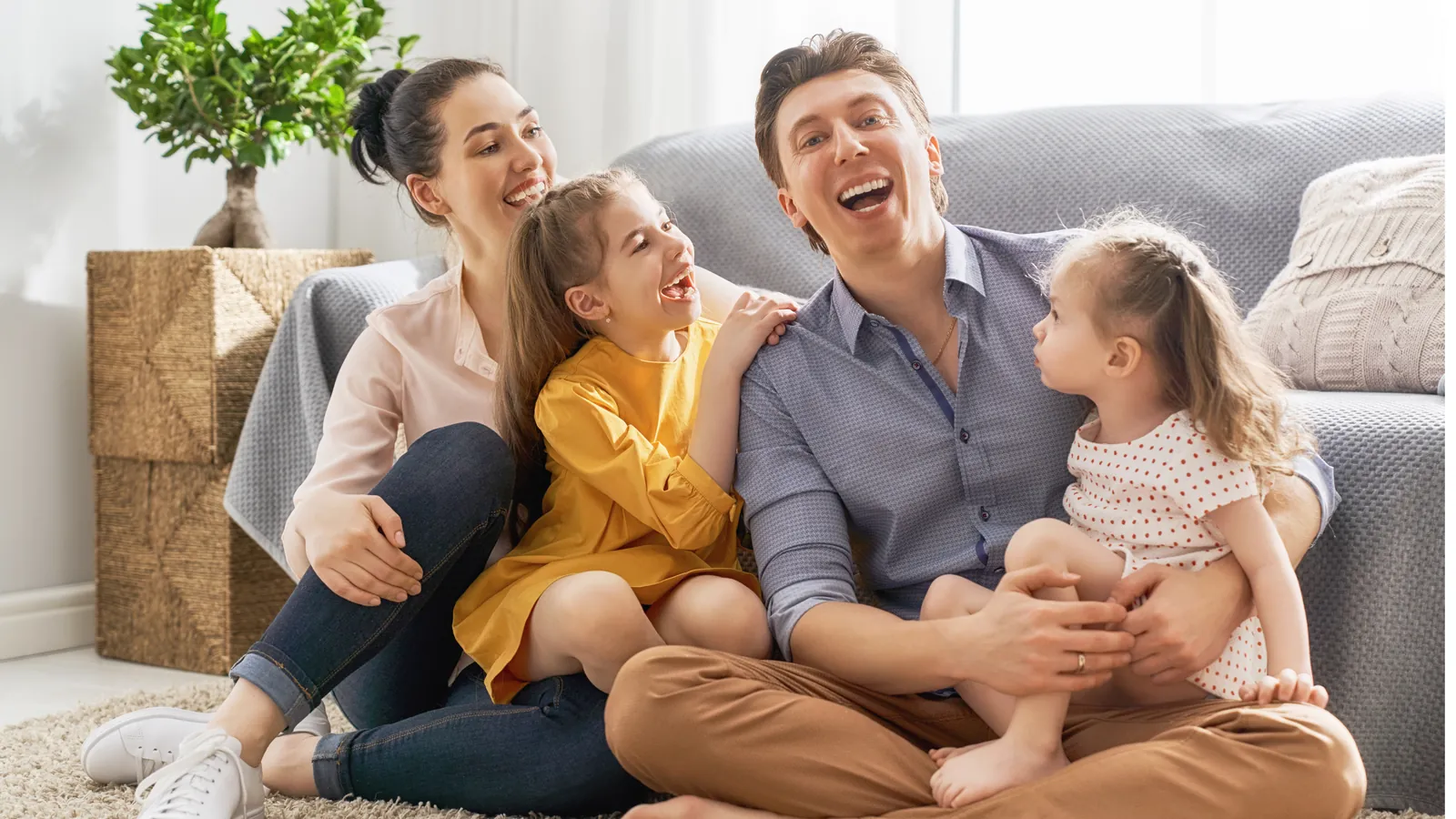 Parents laughing with their two young daughters at home