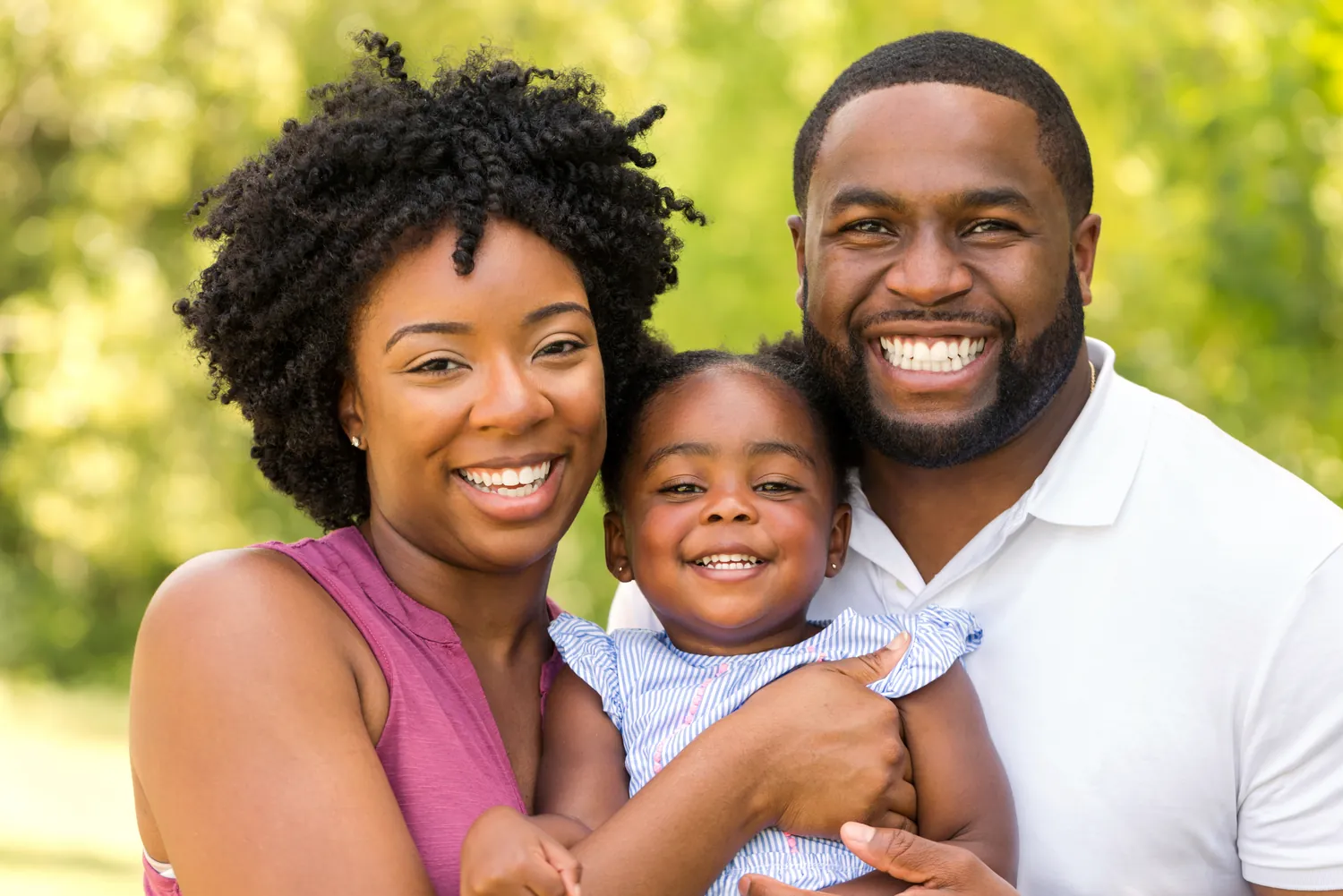 Smiling parents holding their toddler outdoors