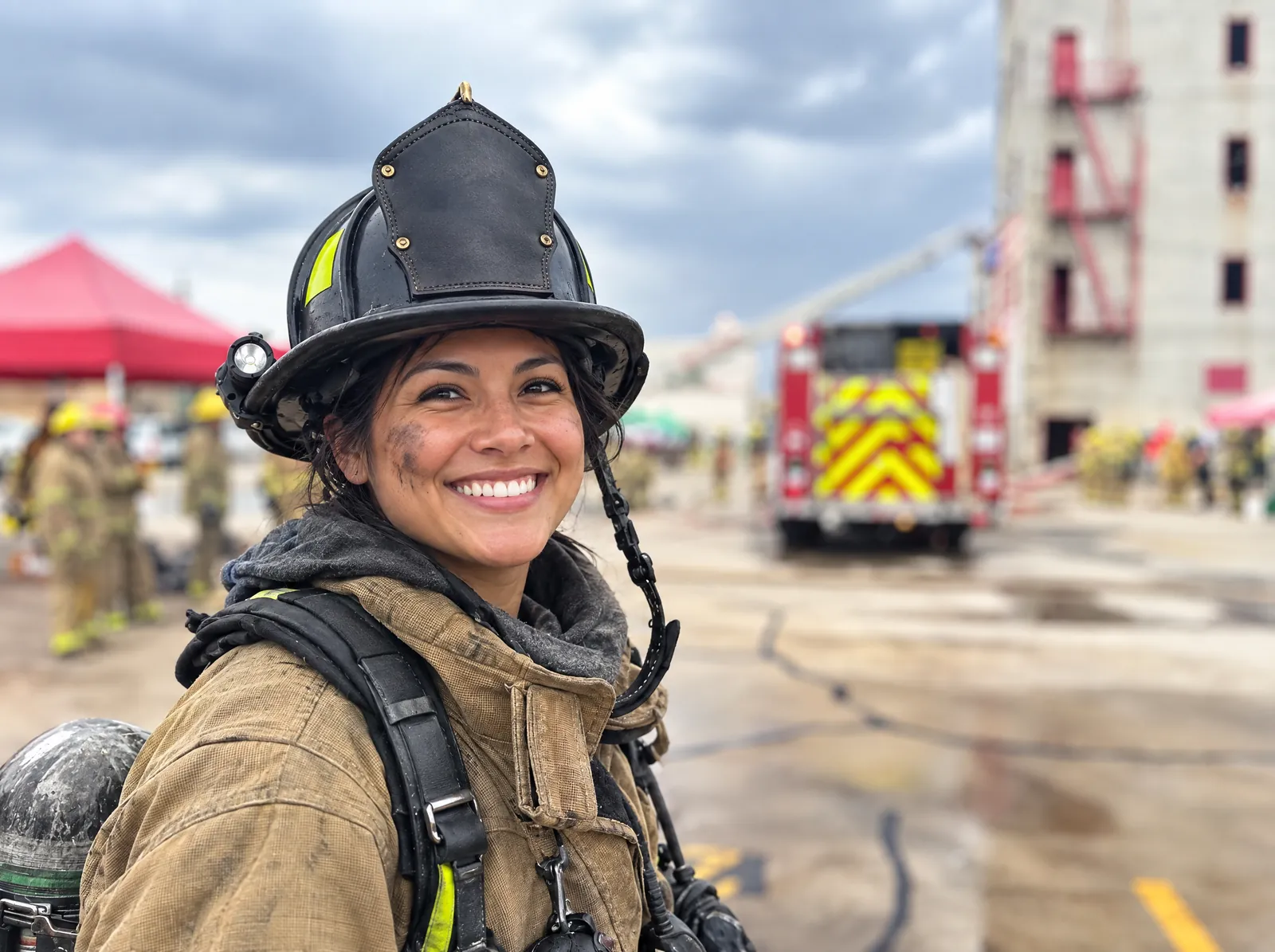 Smiling firefighter in turnout gear at a training ground